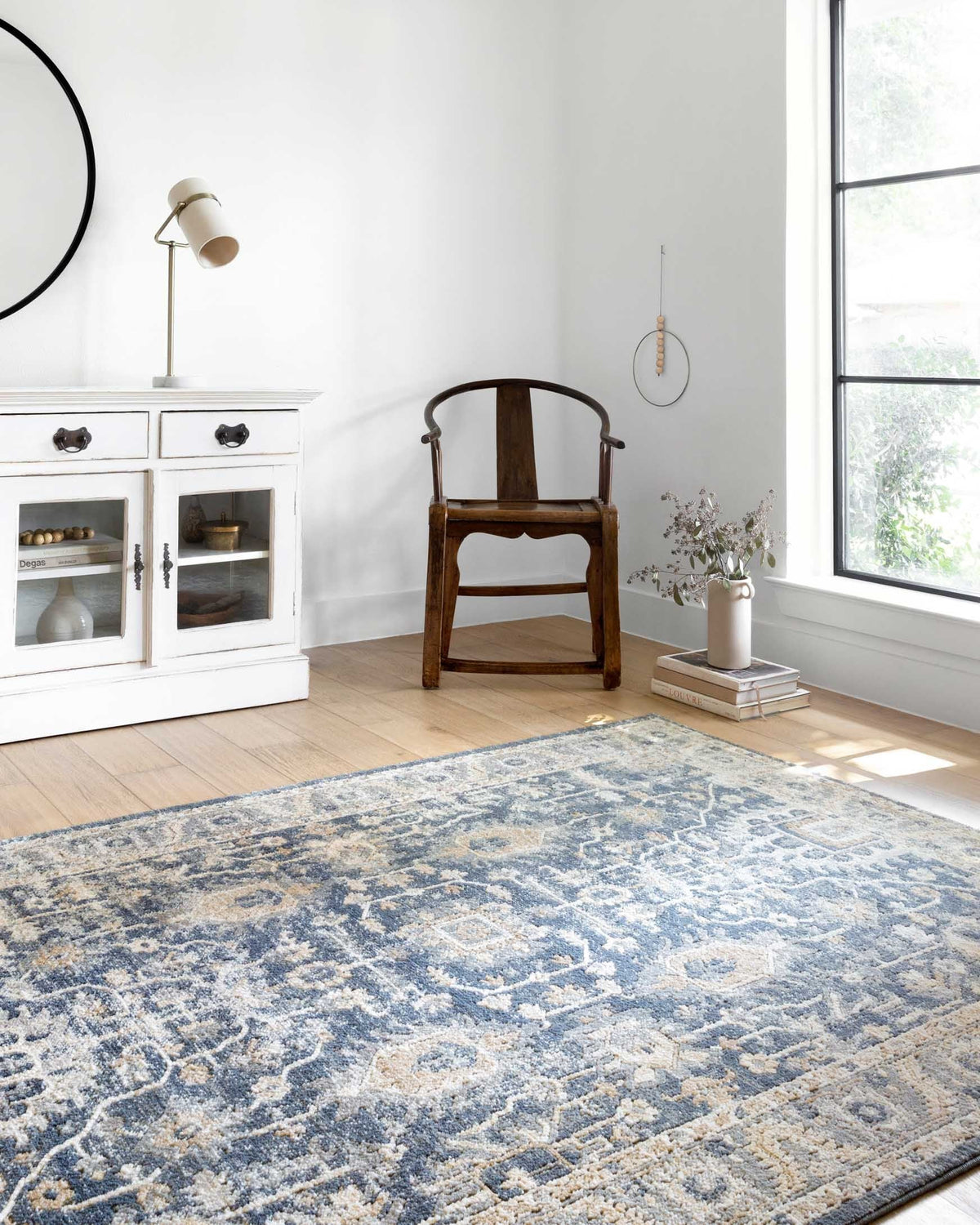 Denim blue and pebble rug with ornate abstract design, shown on the floor.