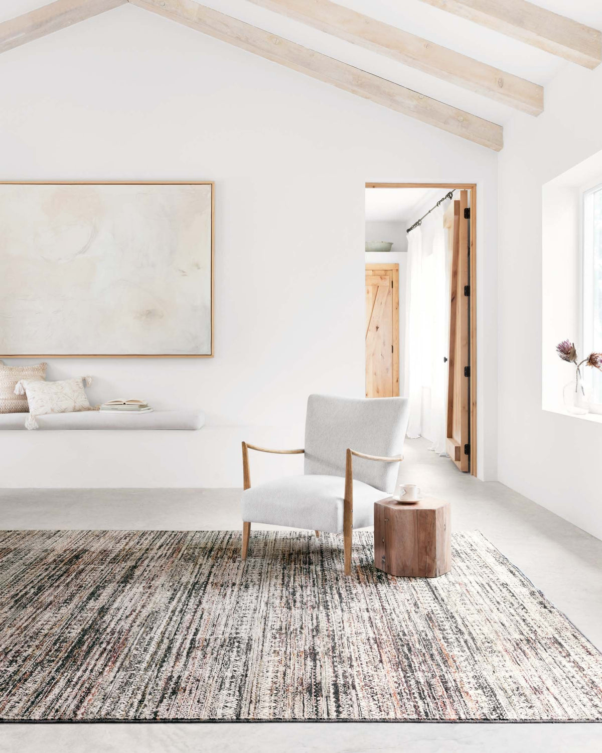 Grey rug with multicolor stripes, placed on living room floor under chairs
