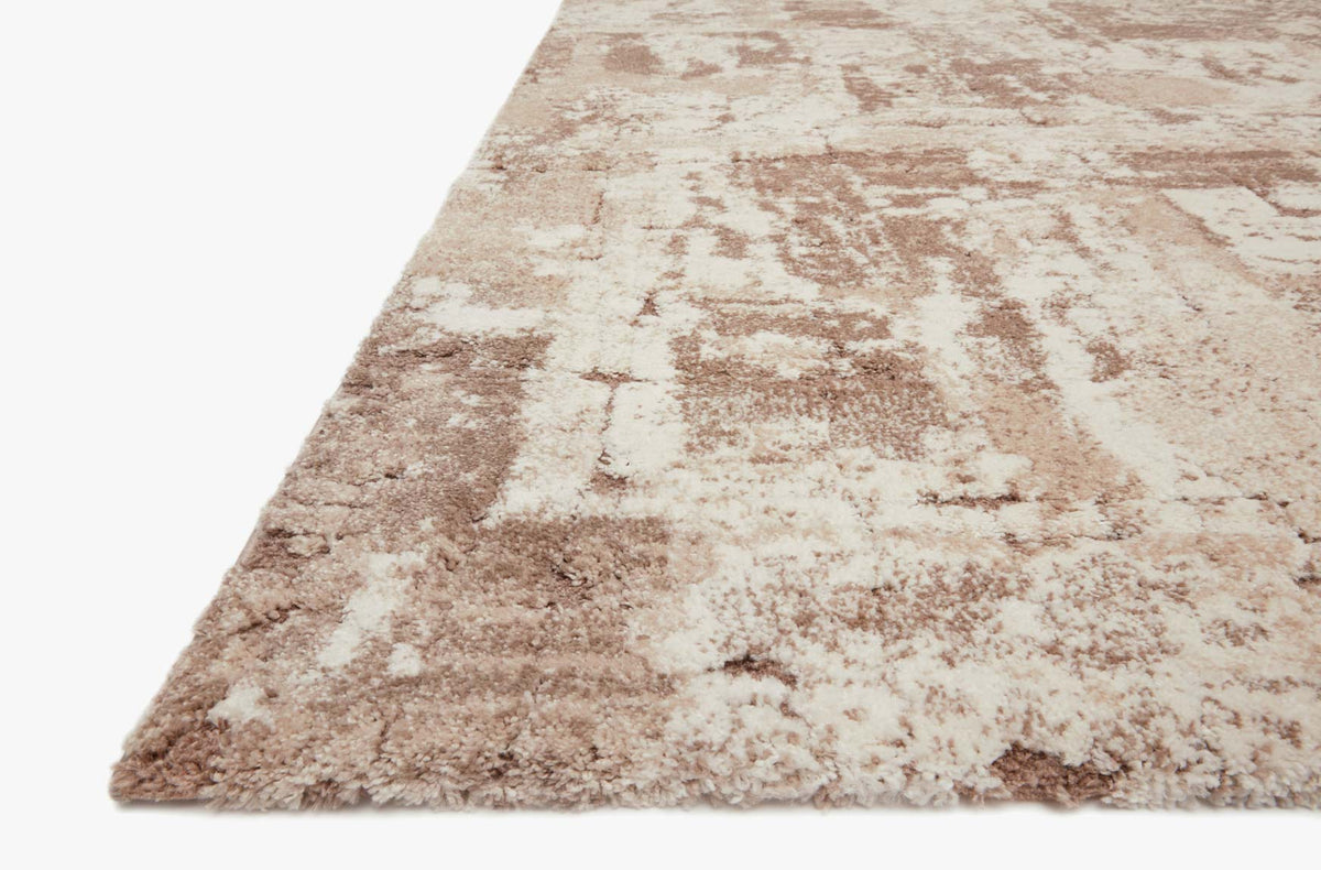 Beige and taupe rug corner with distressed abstract block pattern pile edge