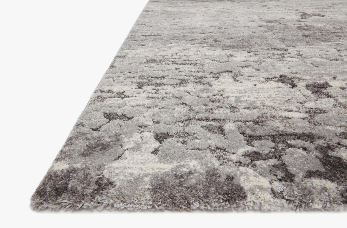 Charcoal and grey power-loomed rug corner with abstract distressed motif and serged edge.