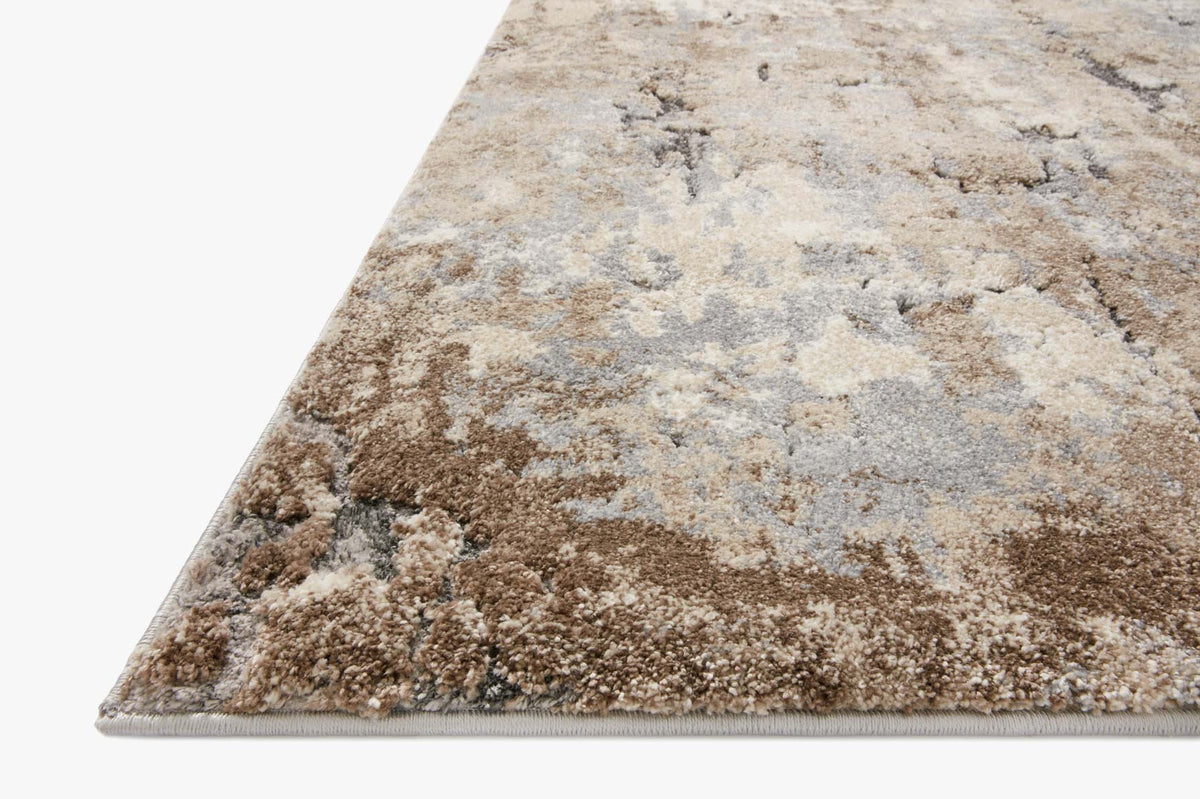 Corner view of power-loomed rug with abstract distressed pattern in beige and gray