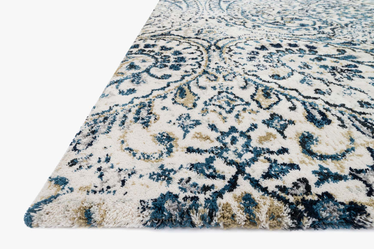 Corner view of ivory rug with indigo floral and scroll medallion pattern, textured pile