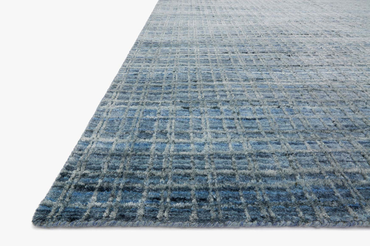 Corner view of blue hand-loomed transitional rug with low-pile grid texture