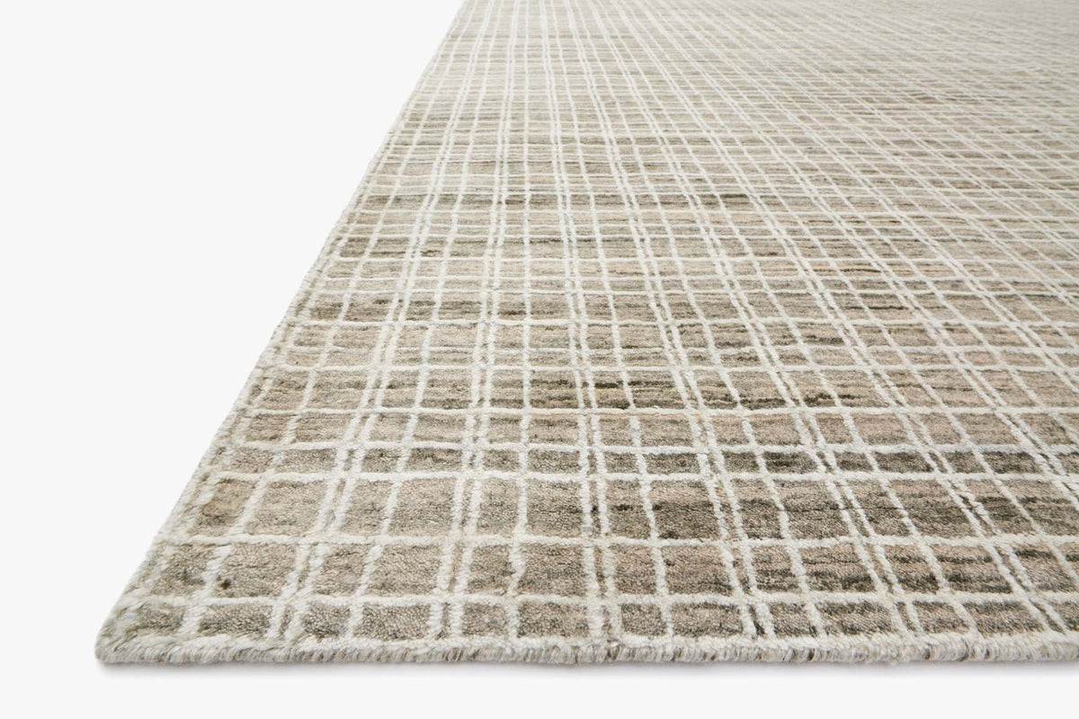 Taupe hand-loomed rug with open grid lines and low, textured pile; corner view