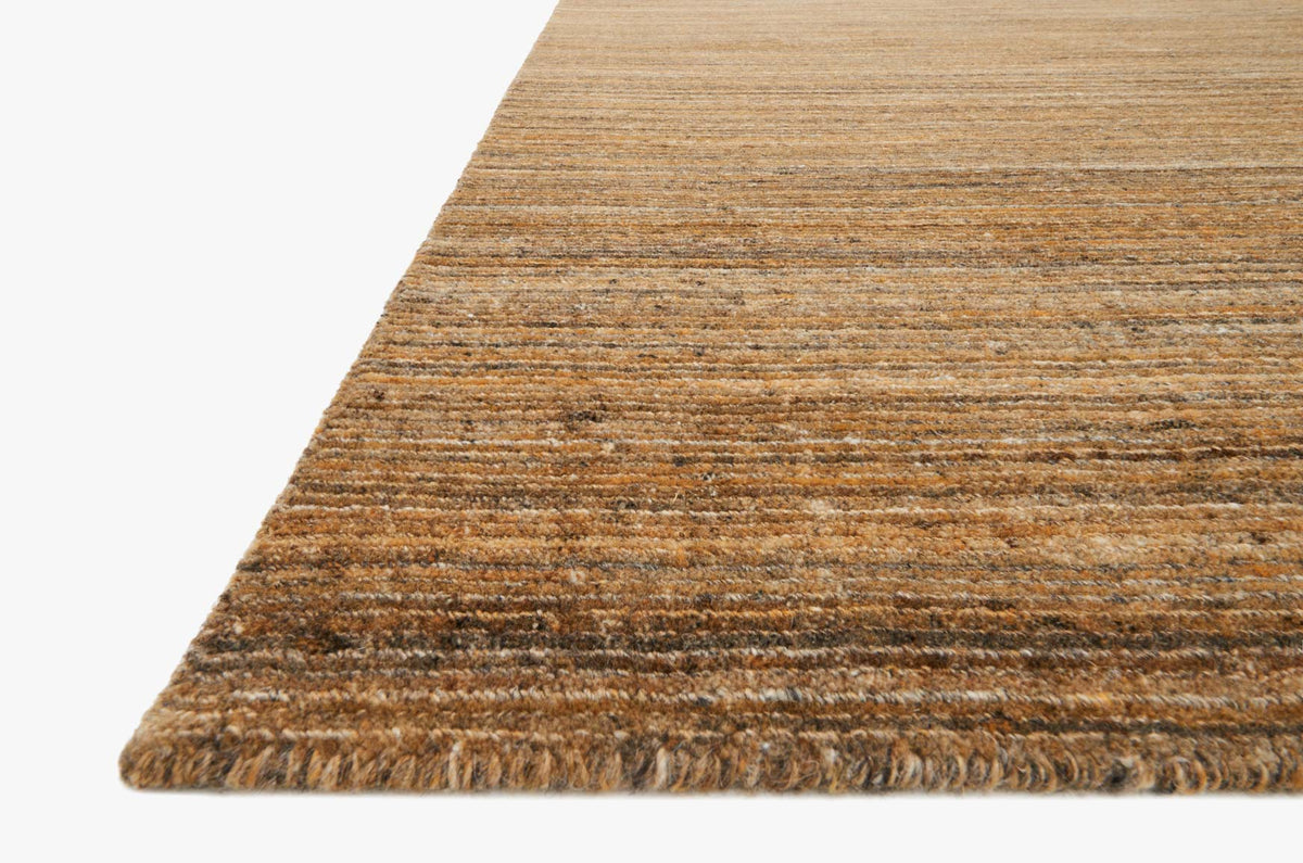 Hand-loomed rug corner detail in amber with short fringe and horizontal stripes