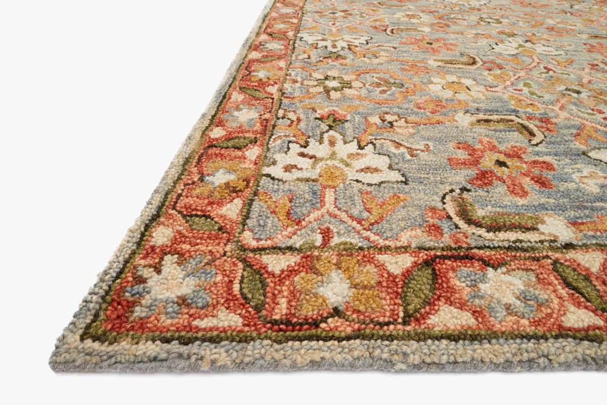 Hooked rug corner detail with slate background, terracotta and green floral motif