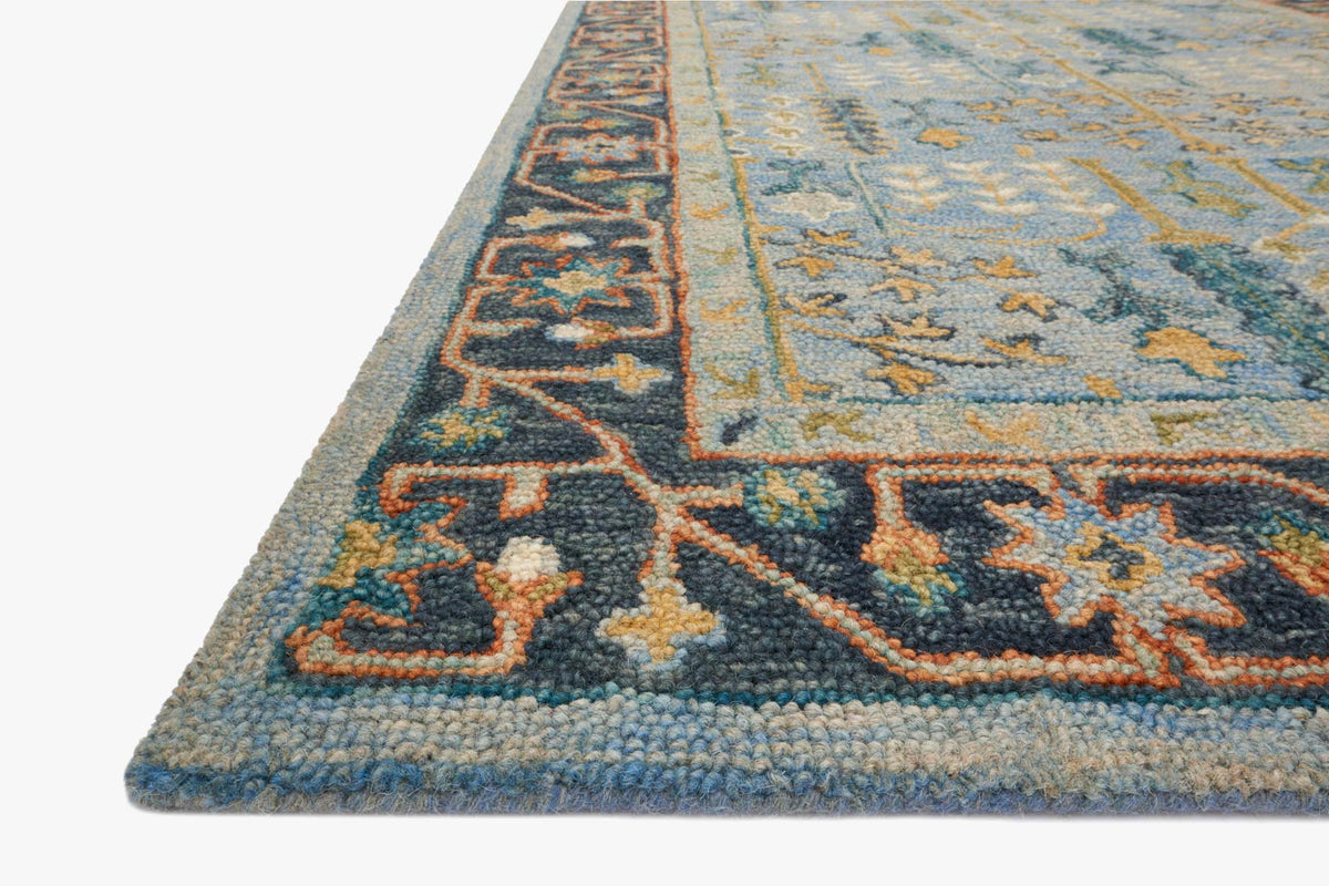 Blue traditional hooked rug corner detail with dark border and patterned medallion