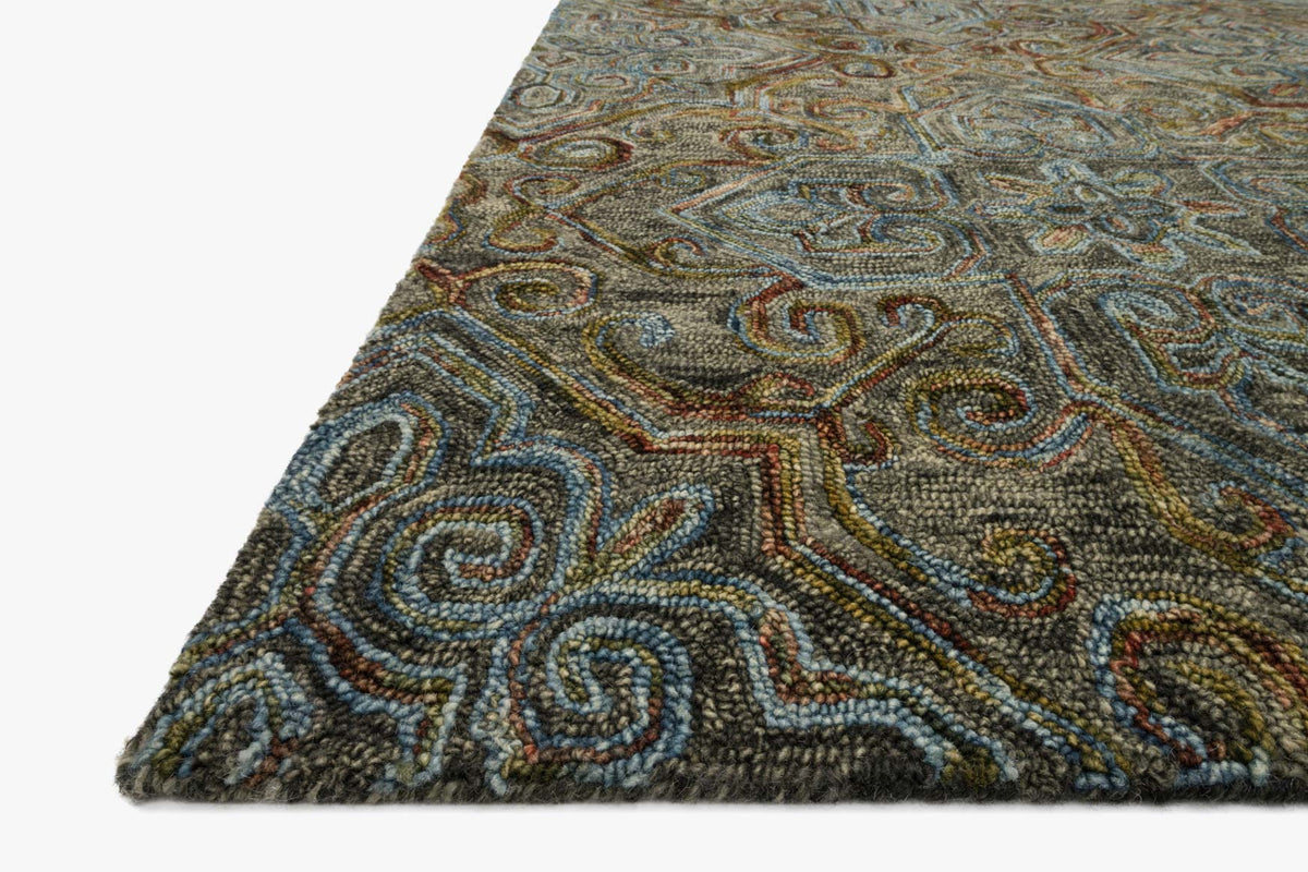 Corner view of traditional hooked rug, dark charcoal texture with teal and tan curls