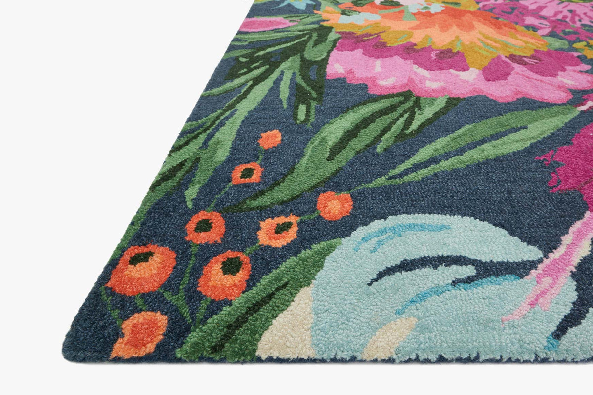 Hooked rug close-up corner with dark blue leaves and orange dots over a light oval