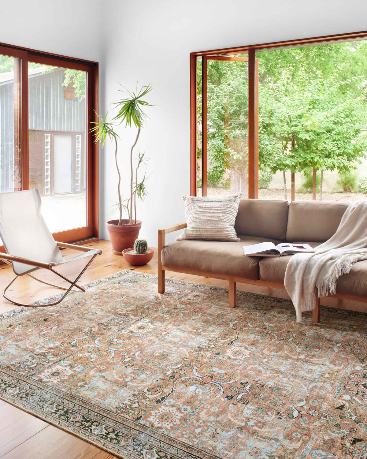 Traditional power-loomed rug with blue and auburn ornamental motifs, framed border, in living room