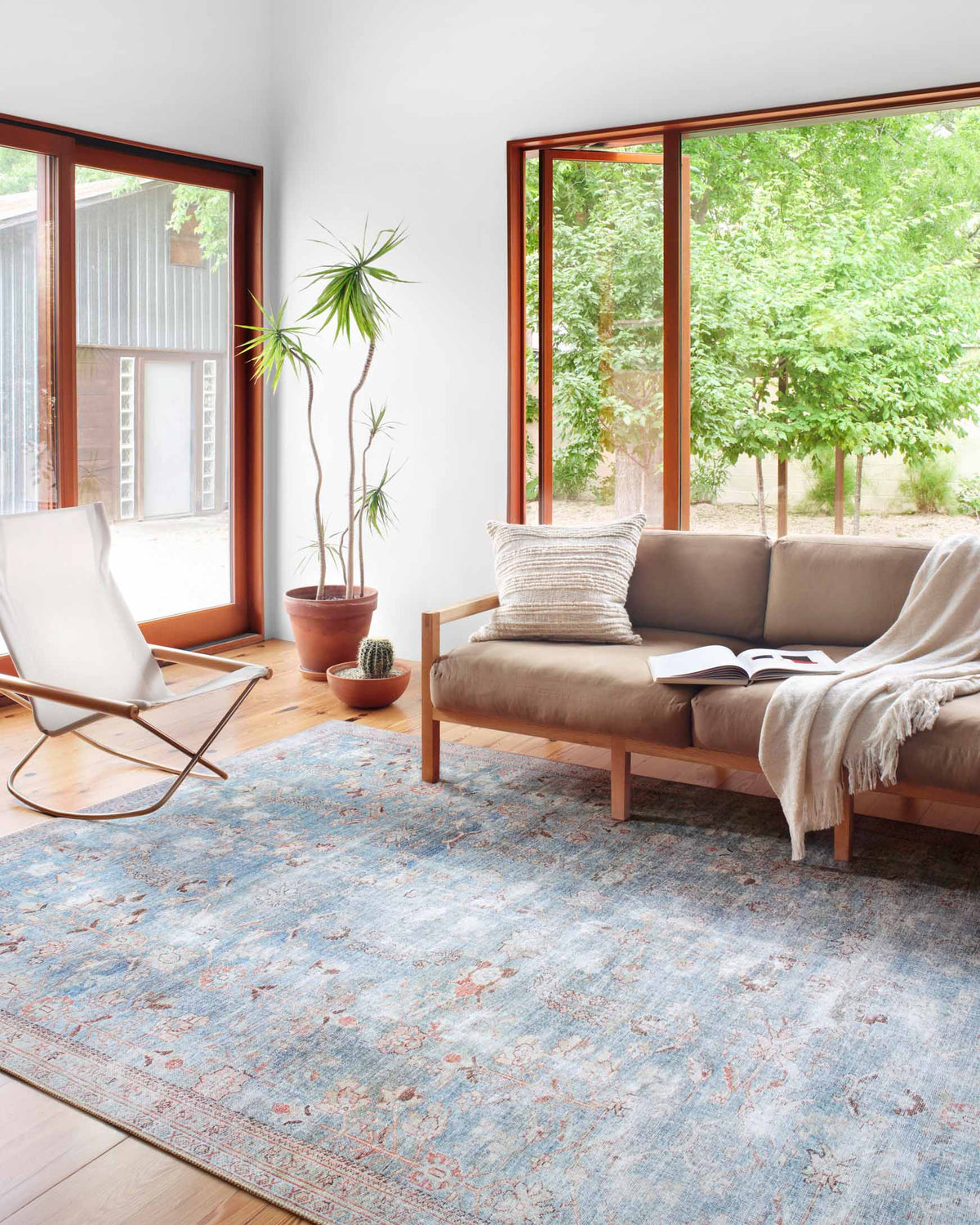 Traditional teal and light blue area rug with distressed pattern and red border