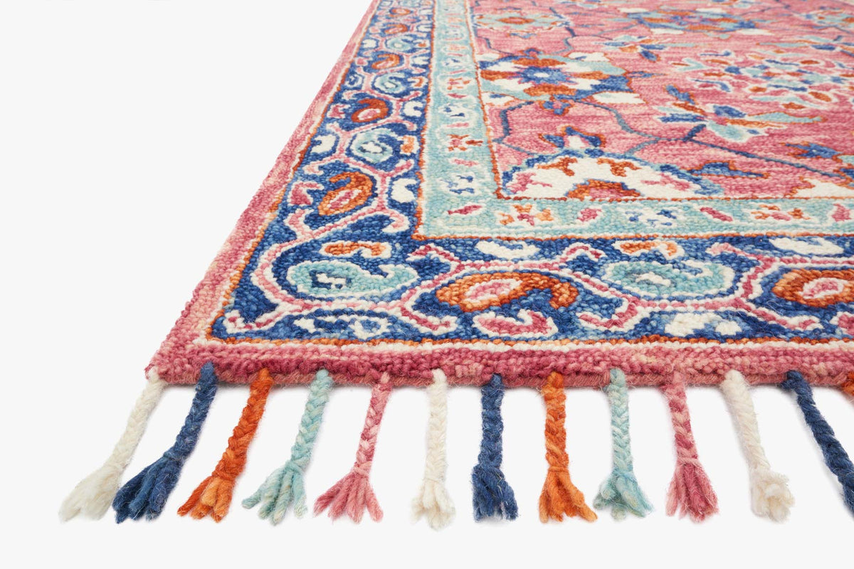 Hooked rug corner in rose and denim with ornate pattern and multicolor fringe