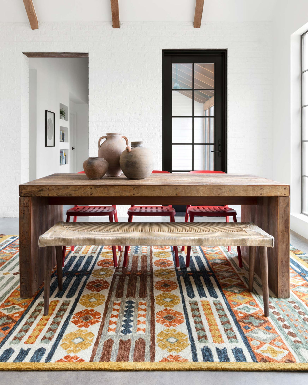 Geometric hooked rug with orange, blue, and cream diamond and stripe pattern, short fringe