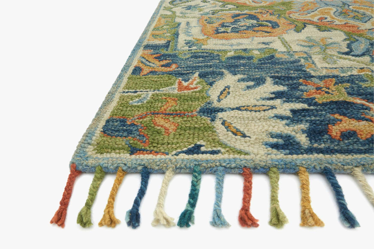 Corner of blue transitional hooked rug with multicolor pattern and tassel fringe