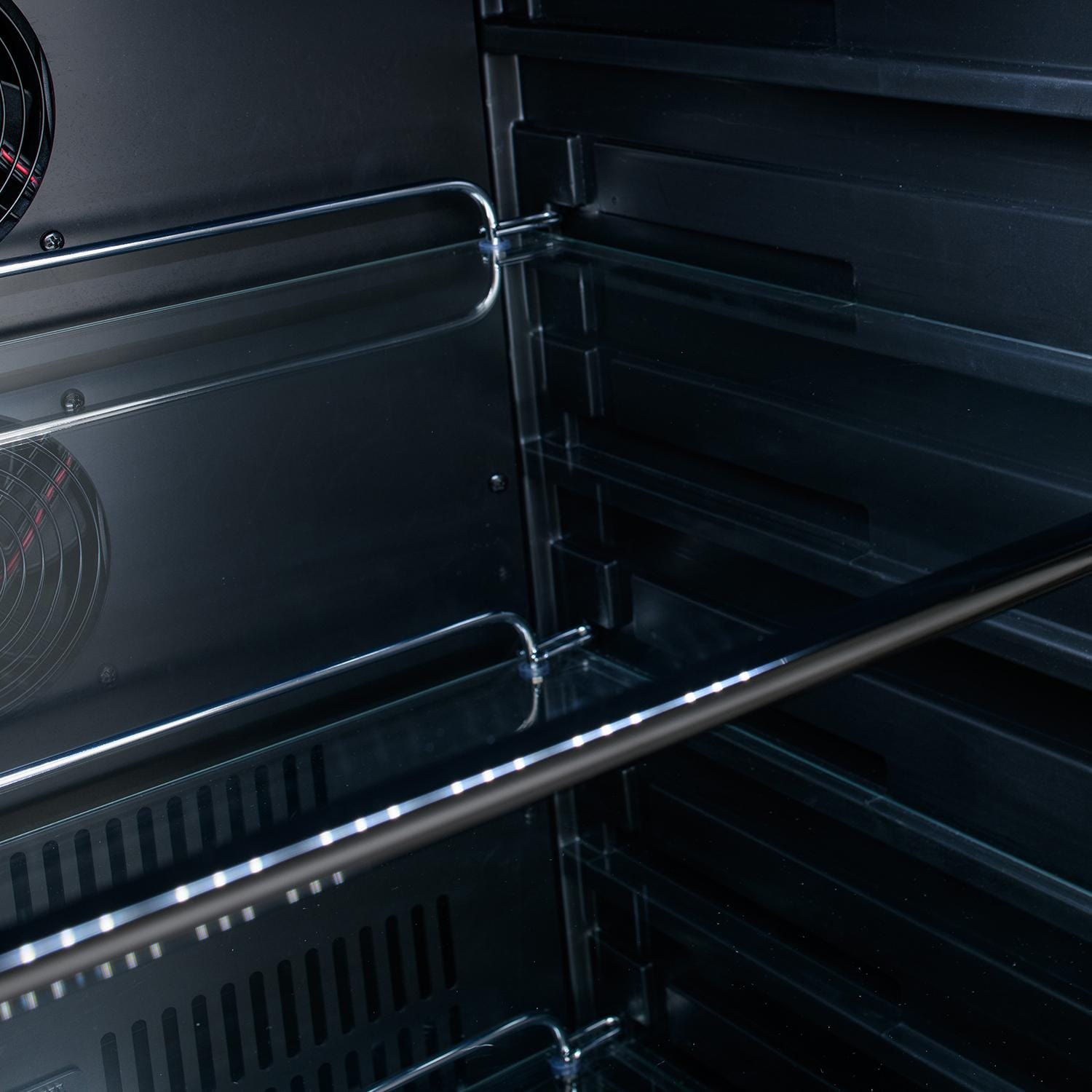 Refrigerator interior with wire shelf rails and circular fan at the left side