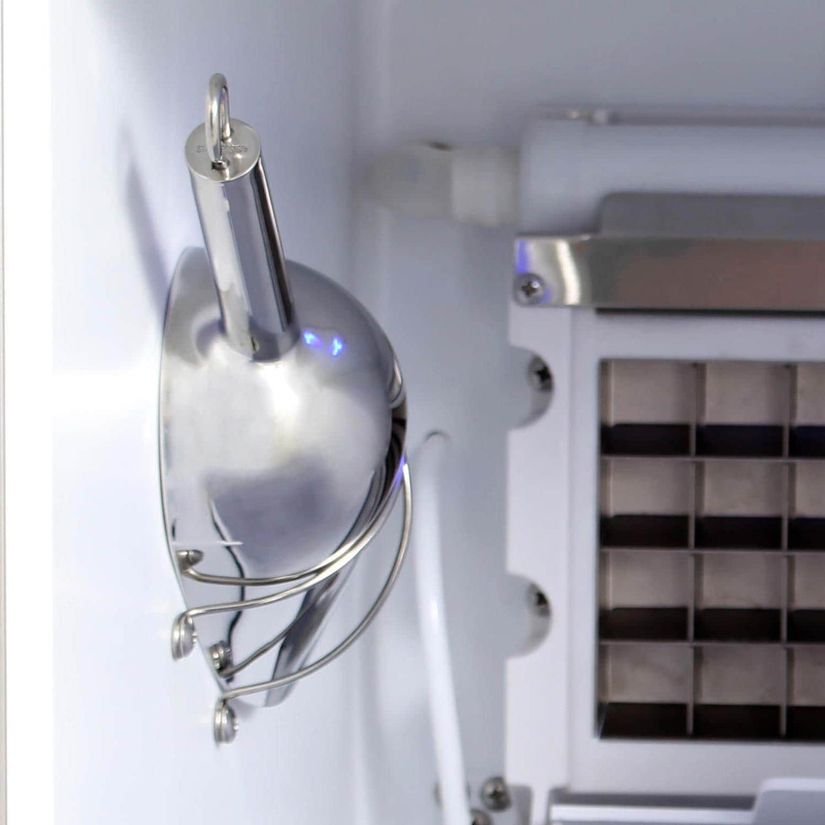 Ice maker interior with metal water distribution fitting and ice chute