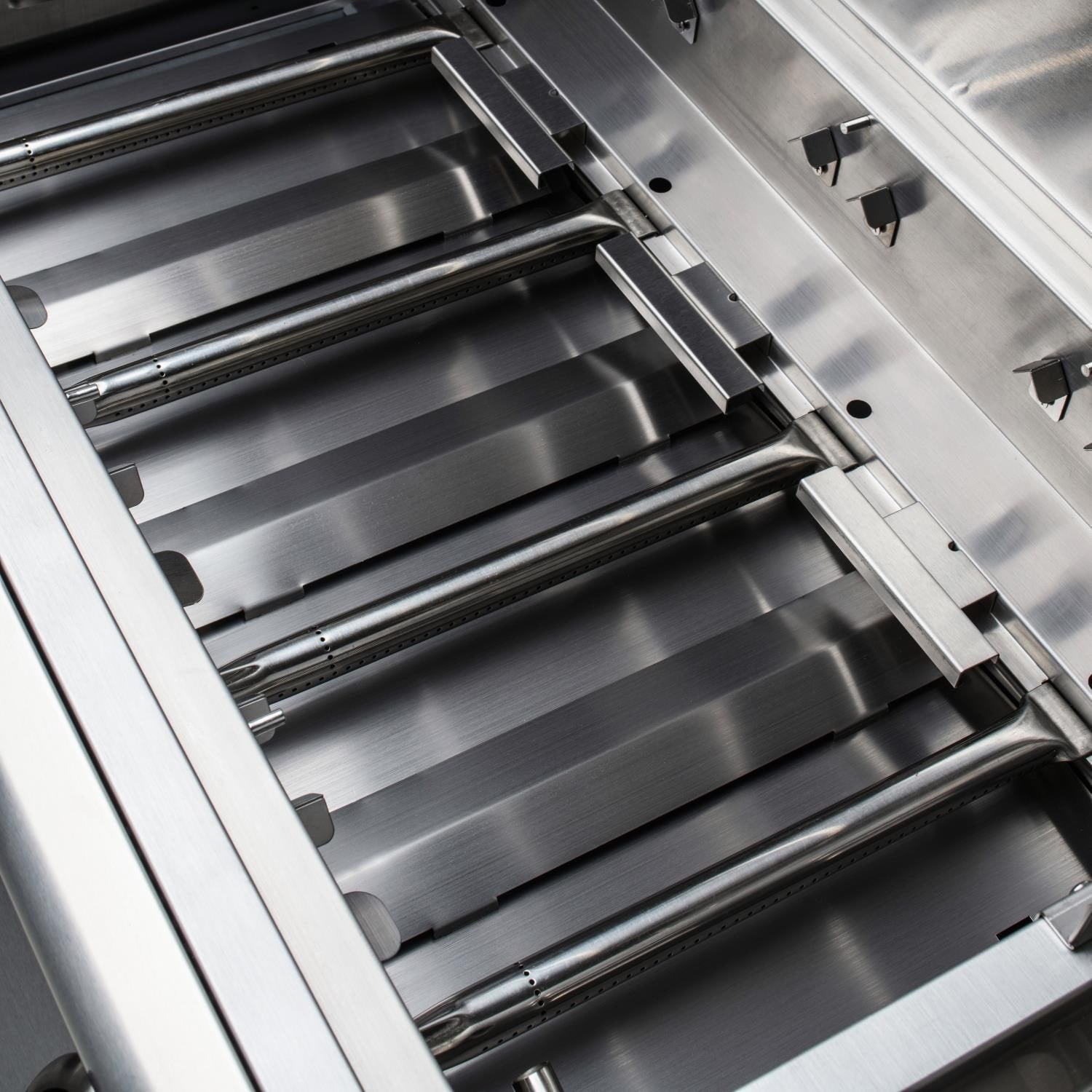 Close-up of stainless steel cooking grates over burner tubes inside grill