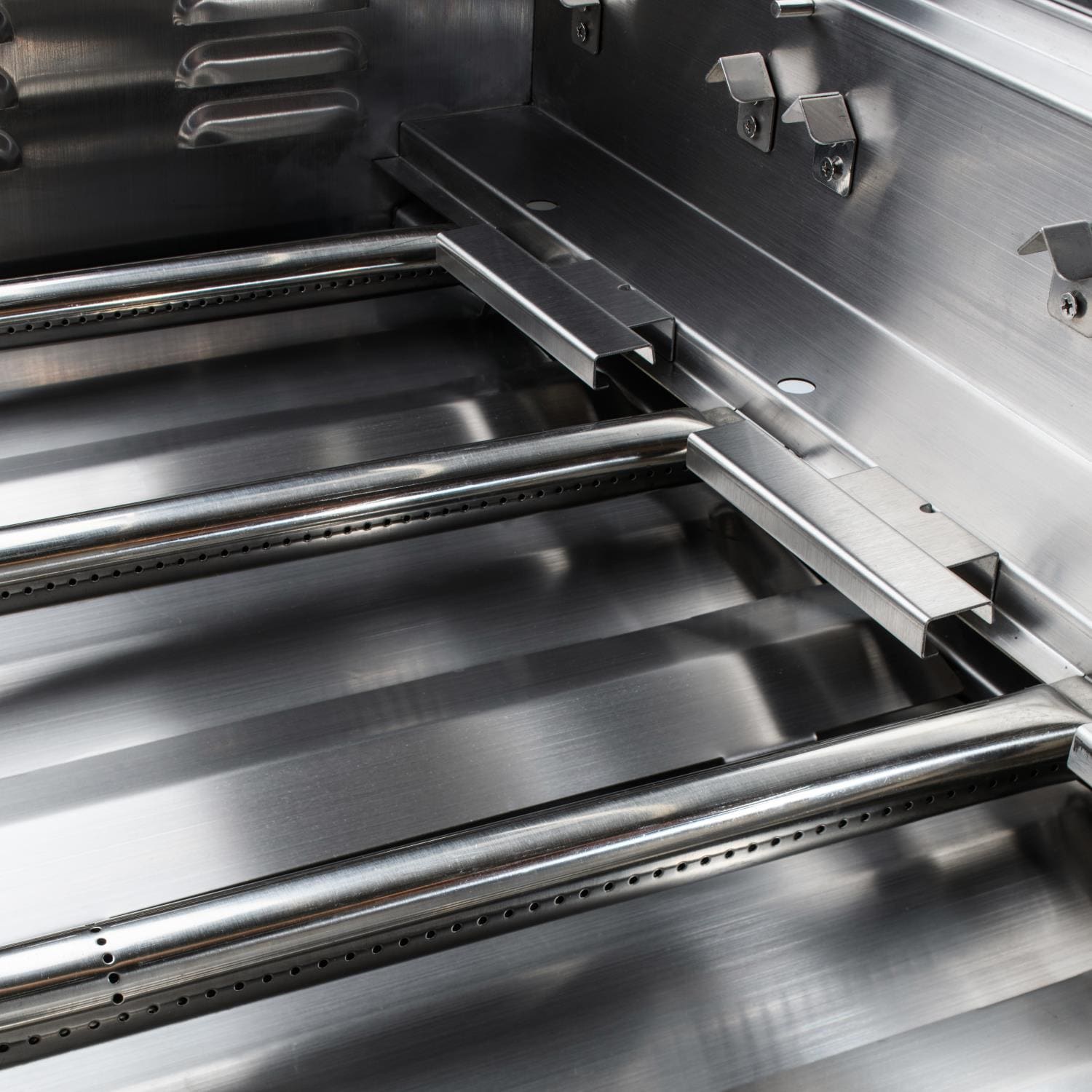 Stainless steel burner assembly inside grill with control rails and shield plates