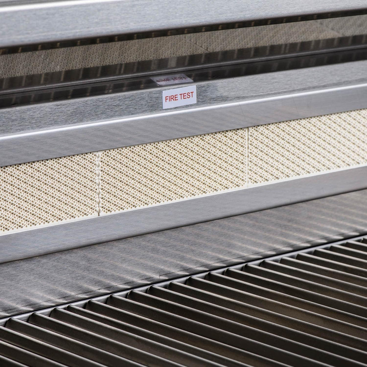 Stainless drip tray area with label marked FIRE TEST and vent channels