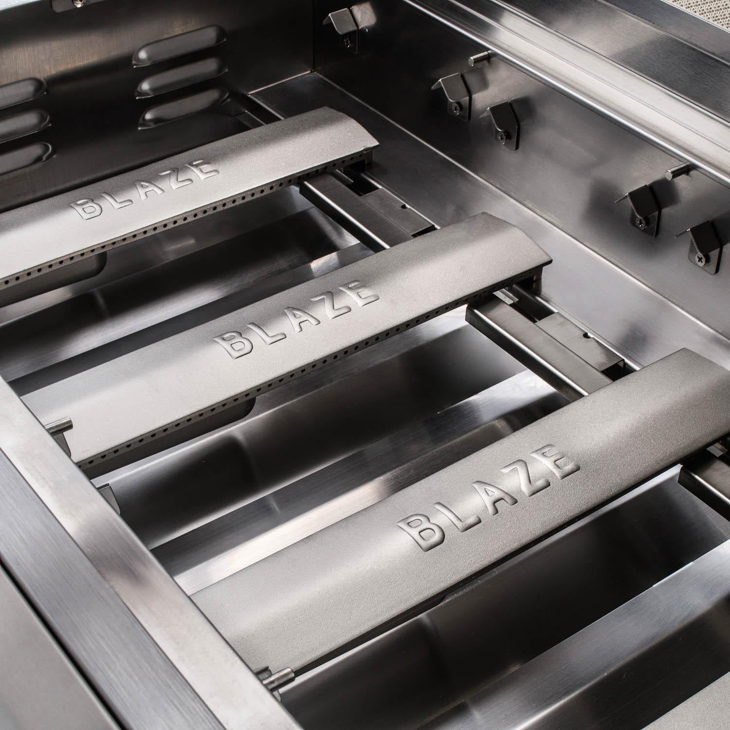 Open stainless grill showing BLAZE-marked inner rails and burner tubes