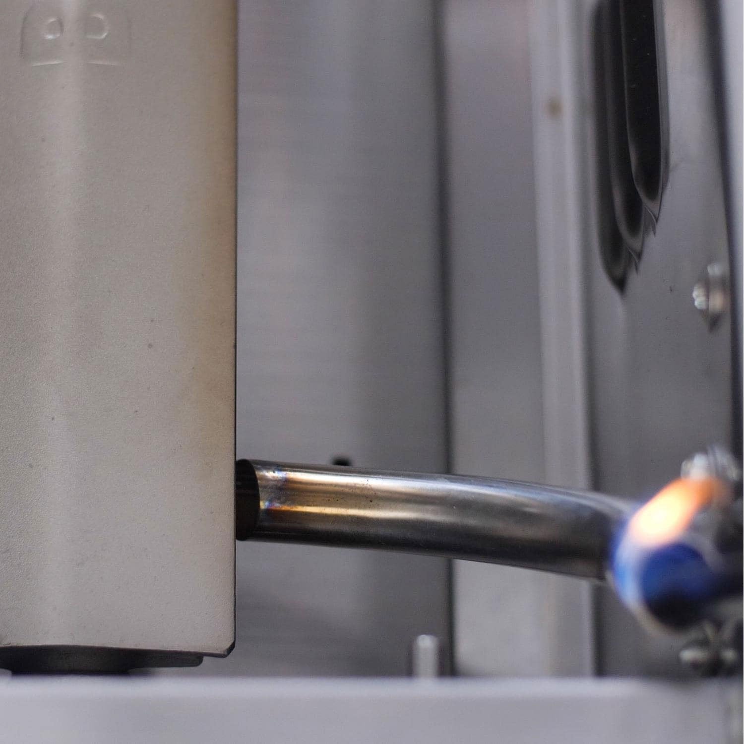 Natural gas grill burner tube inside stainless steel firebox