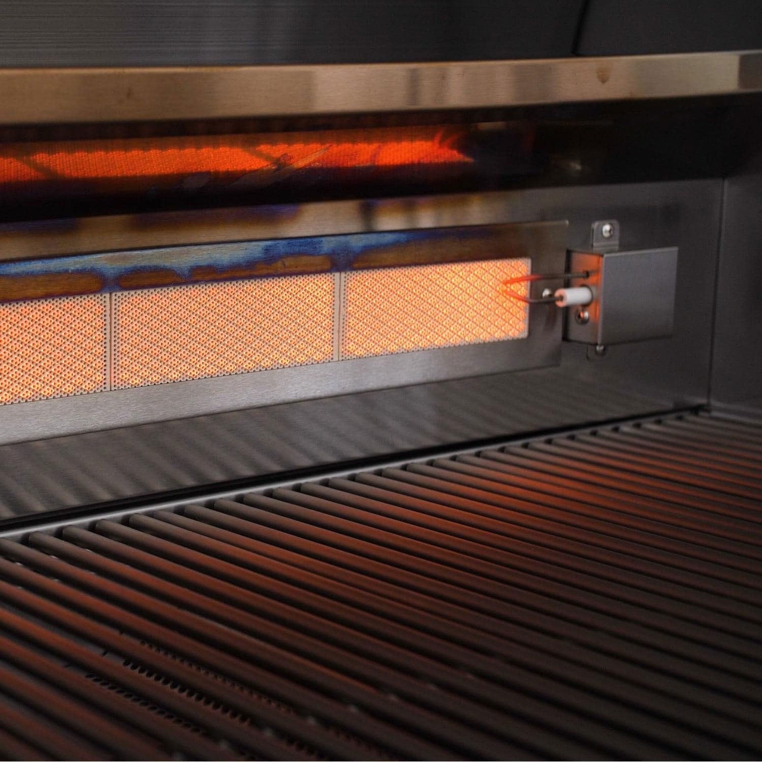 Built-in grill burner with orange glow behind cooking grate