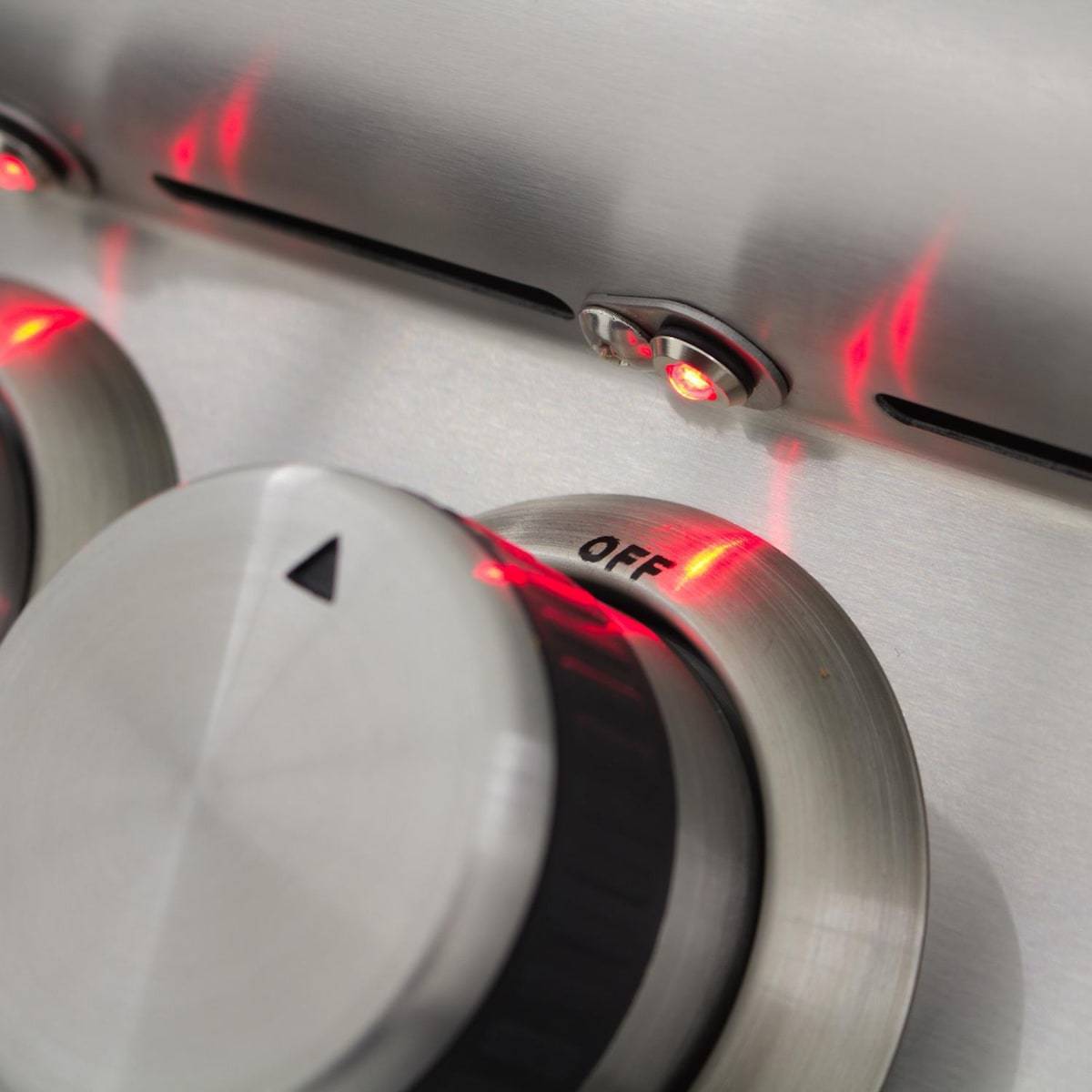 Stainless grill control knobs with glowing red indicator lights and flame glow