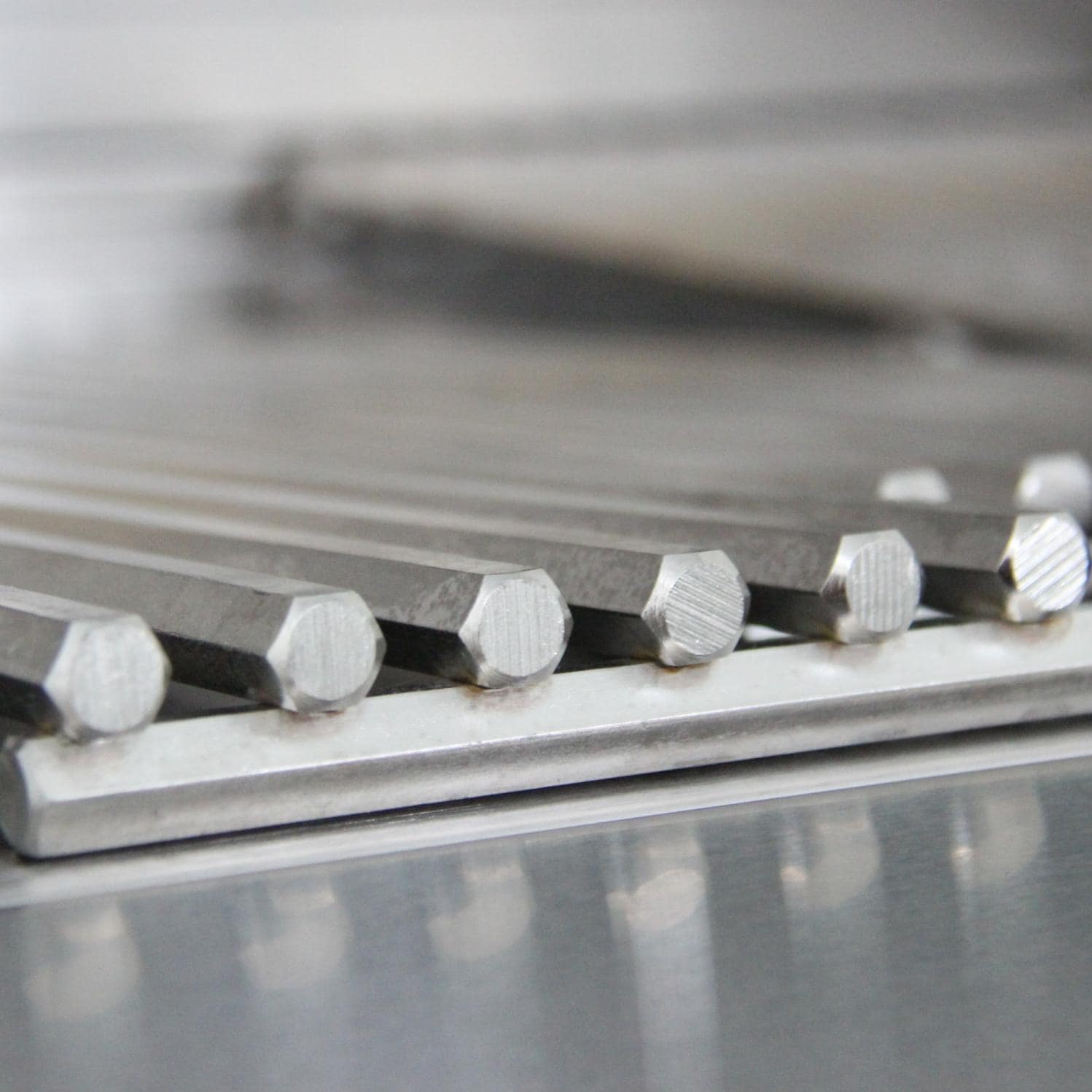 Close-up of stainless steel burner tubes and heat deflector rods inside grill