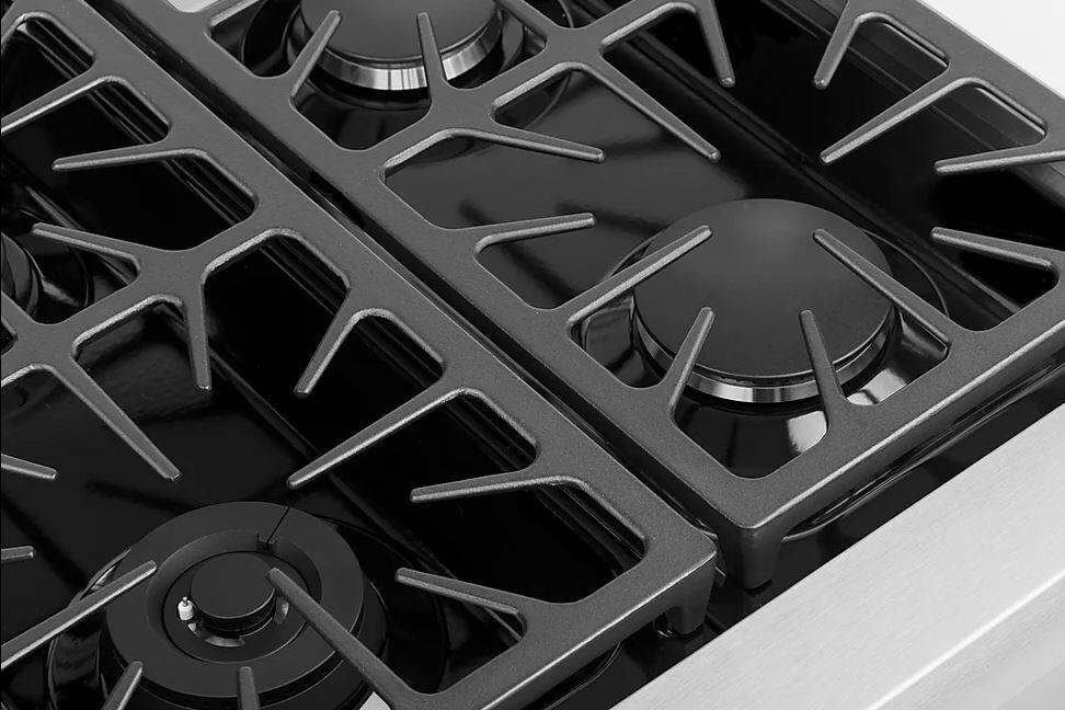 Close-up of black cast-iron burner grates and round burner caps on a stainless gas cooktop