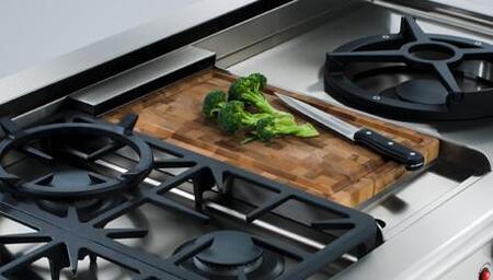 Wooden griddle chopping block with a knife and small pile of green herbs