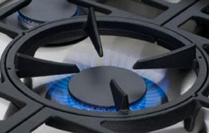 Stainless gas burner with blue flame under a black cast grate