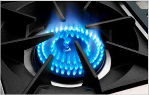 Blue gas flame burning on an open cooktop burner