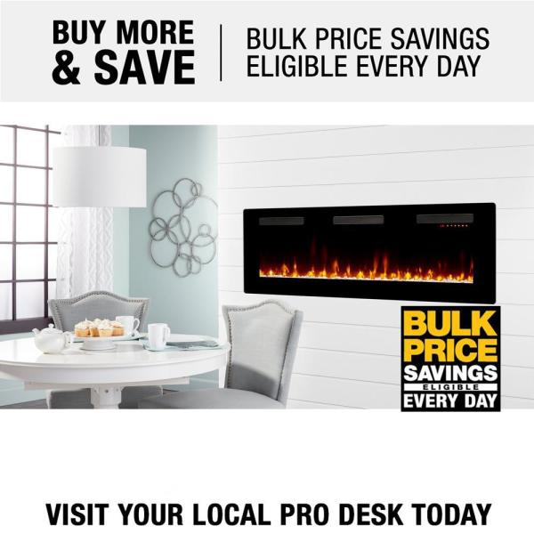 Black linear electric fireplace in a white wall above a seating area with flames