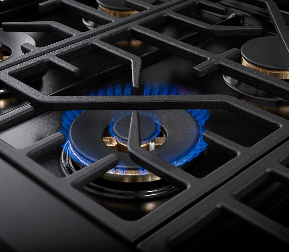 Gas burner with black grate and visible blue flame in stainless cooktop
