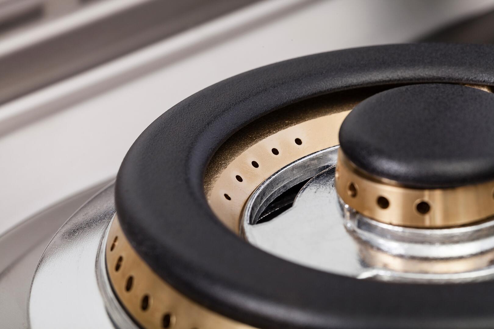 Close-up of dual fuel burner ring with black cap and brass inner parts