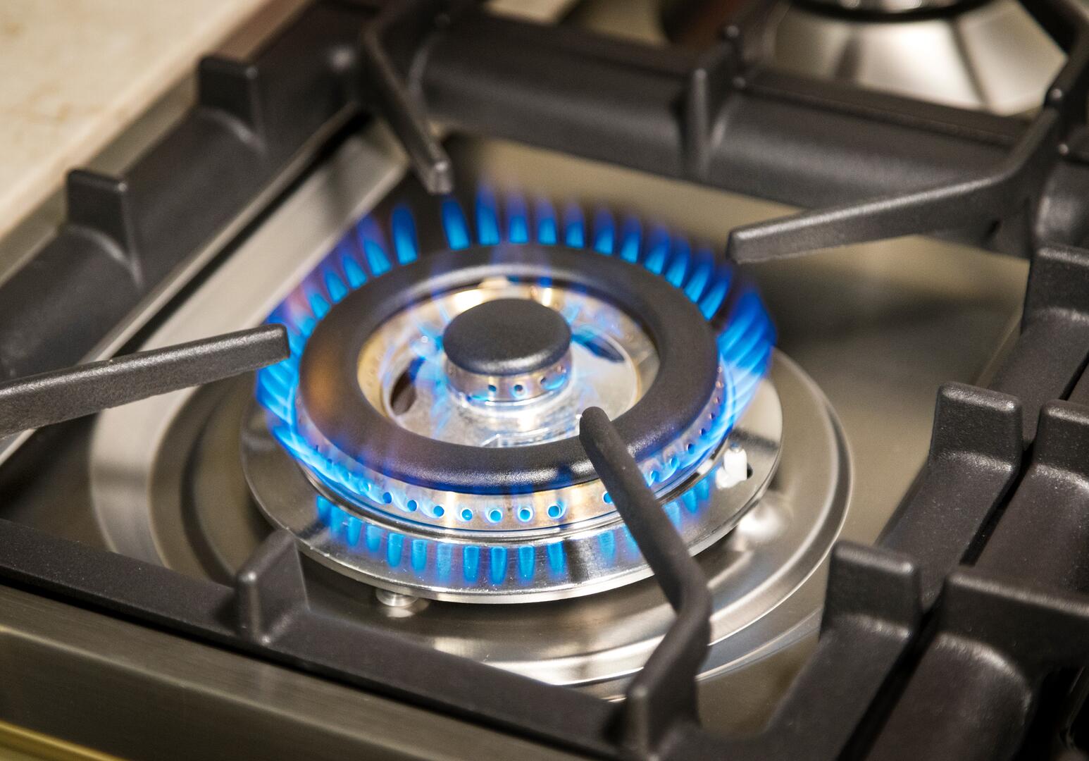 Professional dual fuel range burner head glowing blue under black grate