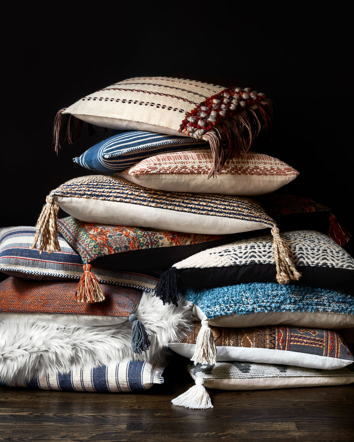 Stacked striped pillows in navy and natural, each with corner tassels