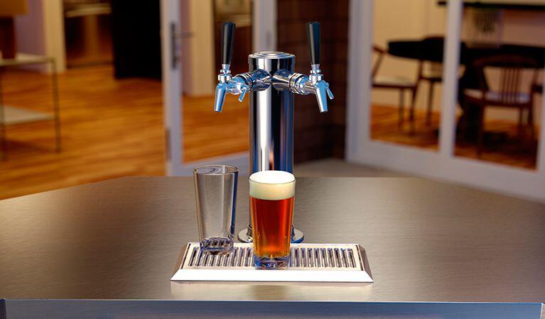 Stainless beer dispenser taps with a glass of beer on the drip tray