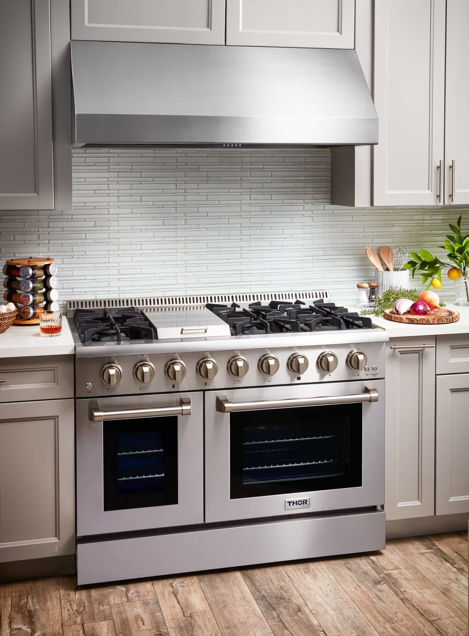Stainless steel dual fuel range and hood package with two ovens, front view in kitchen.