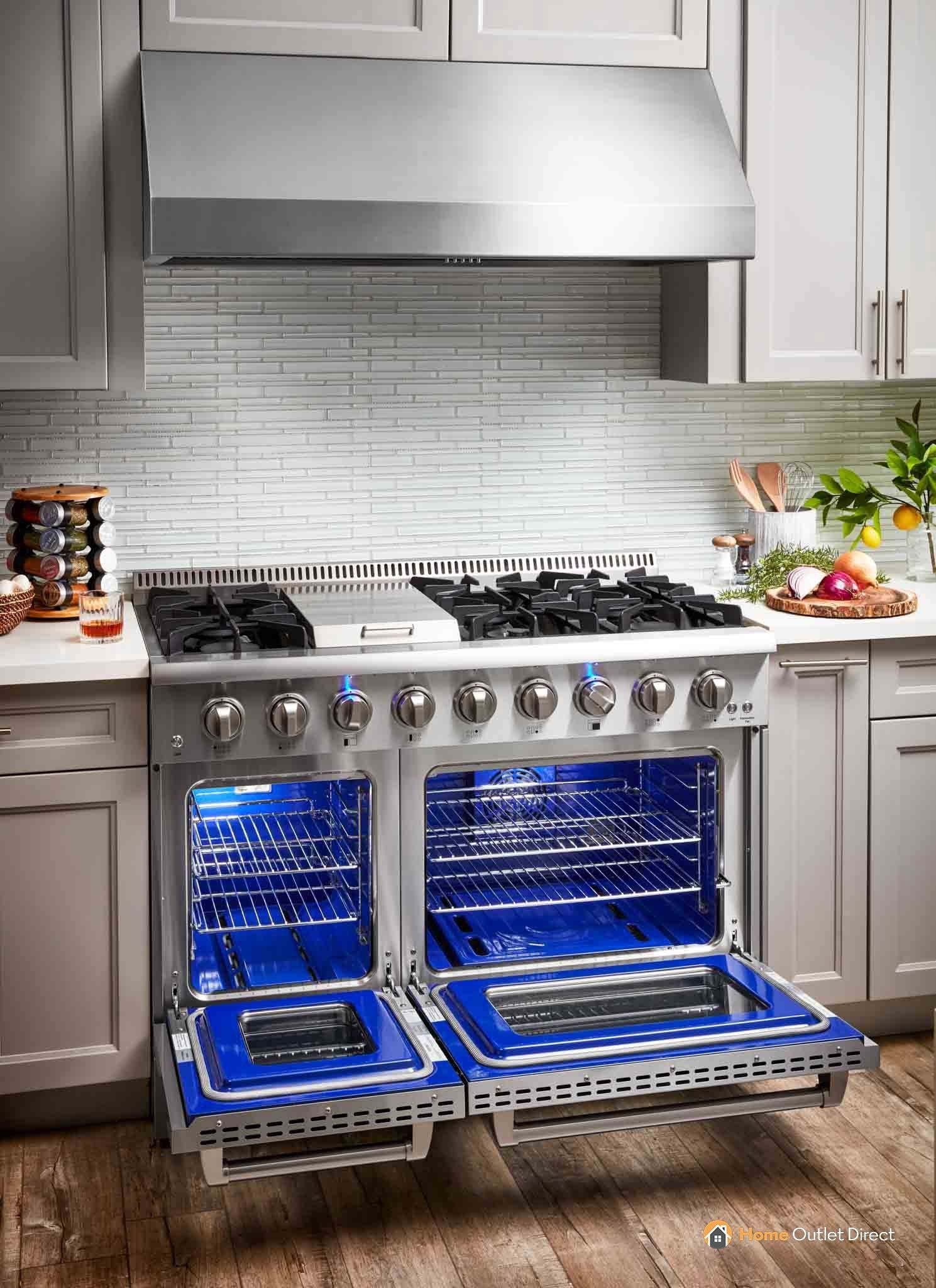 Stainless steel dual fuel range with open ovens showing blue racks, kitchen view.