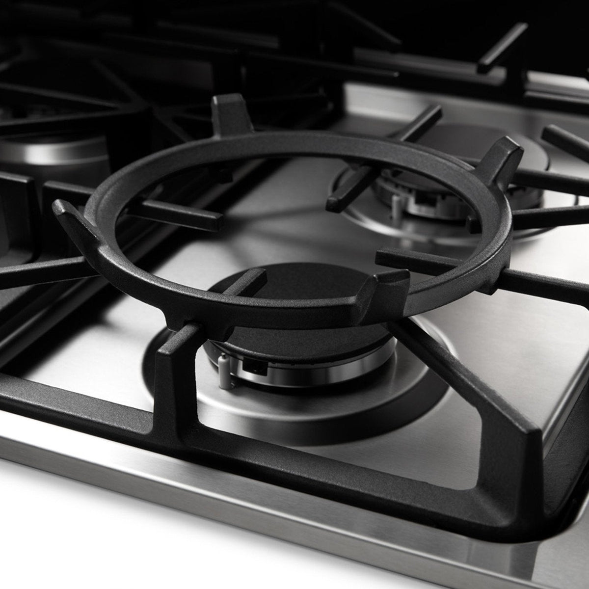 Close-up of black burner grate and circular gas cap on stainless steel cooktop