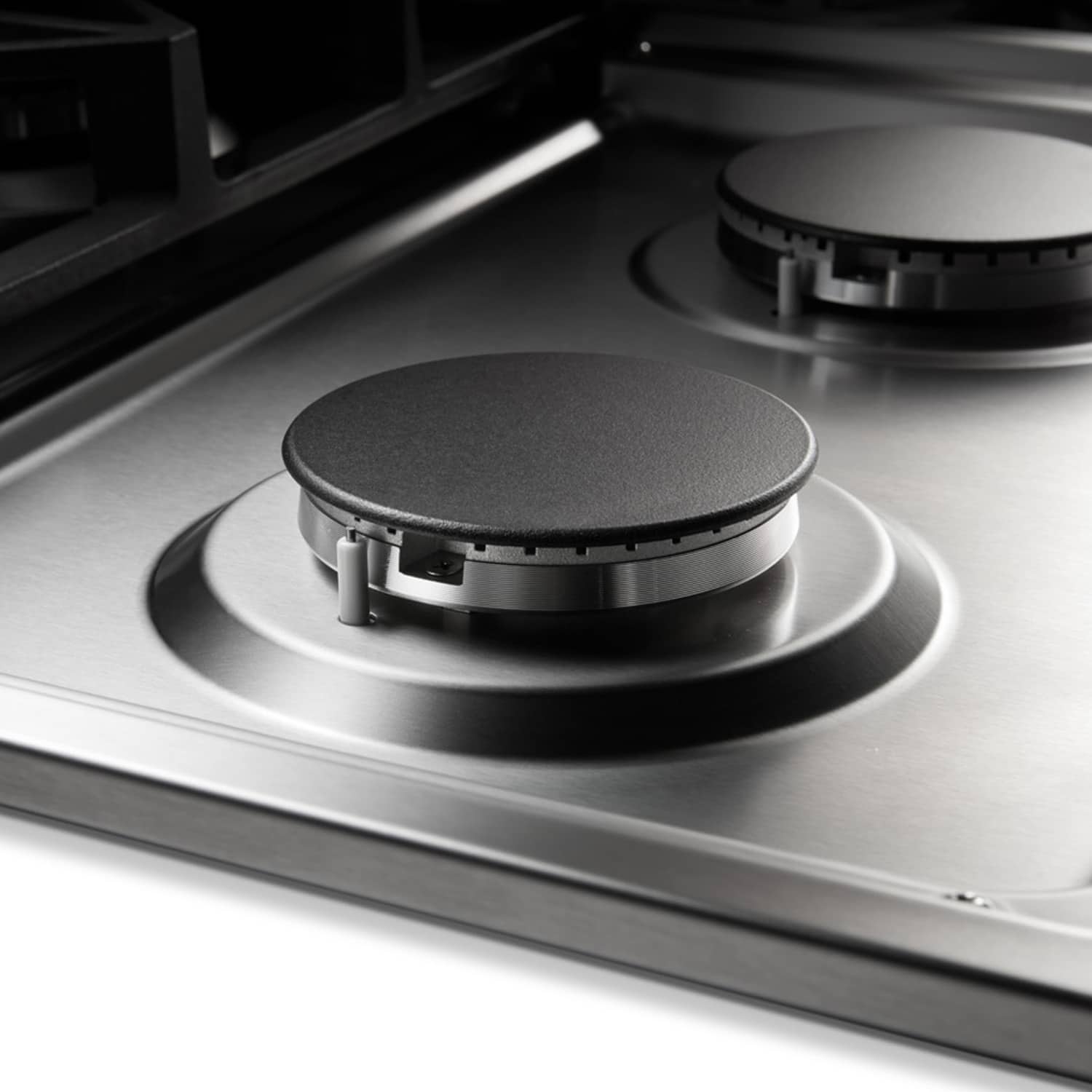 Single burner head on stainless gas cooktop with black burner cap and ring