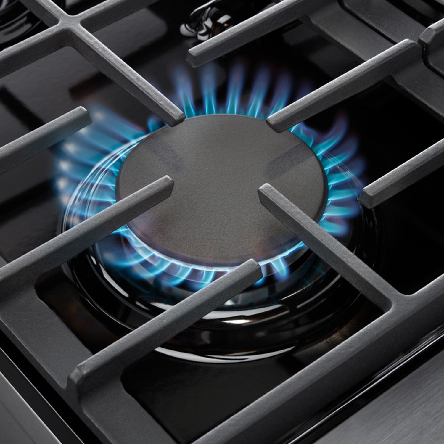 Gas burner grate with blue flame on stainless steel double oven range cooktop