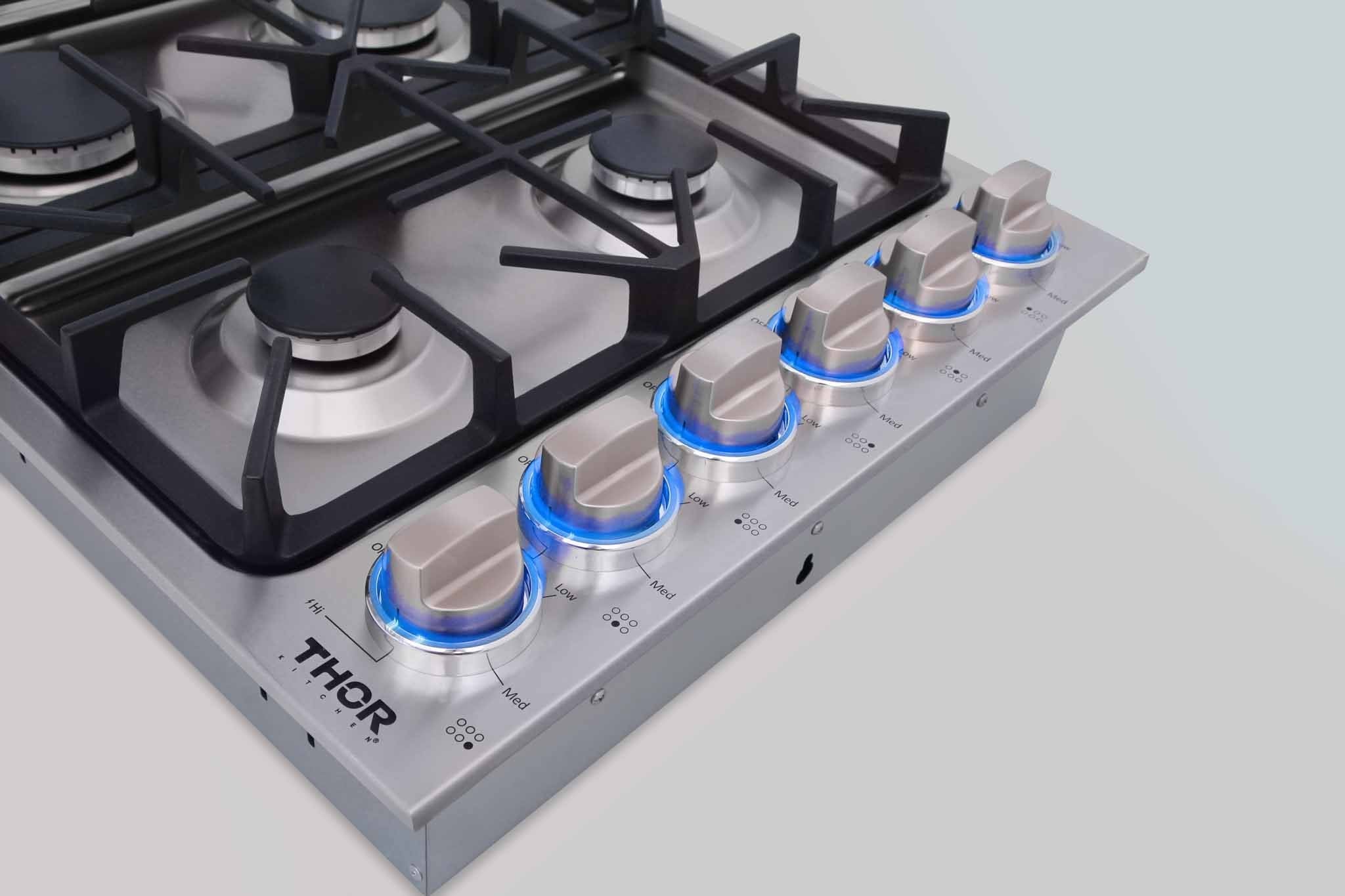 Stainless steel gas cooktop with six burners and blue-lit control knobs