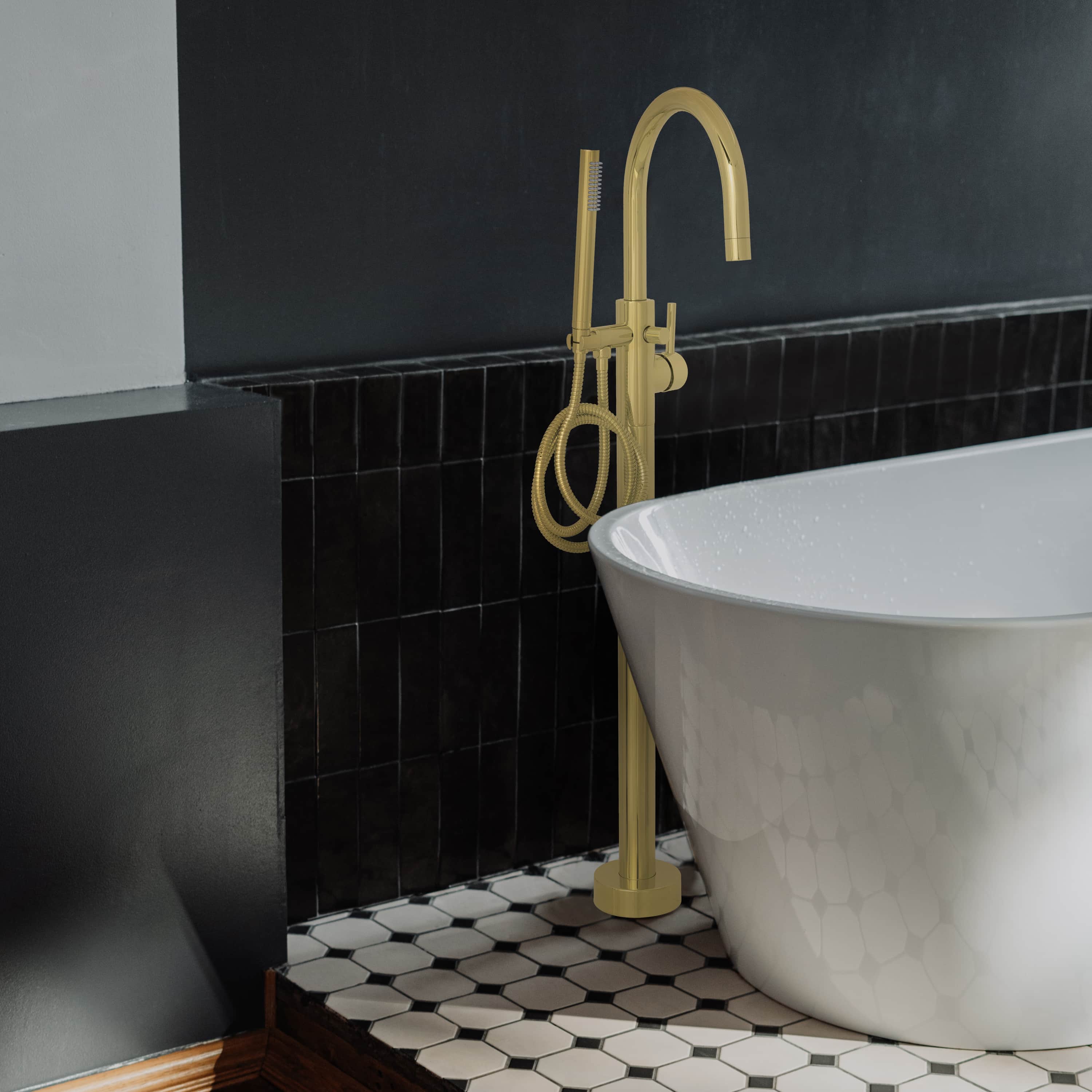 Polished gold bath tub filler with arched spout and coiled hose beside white tub