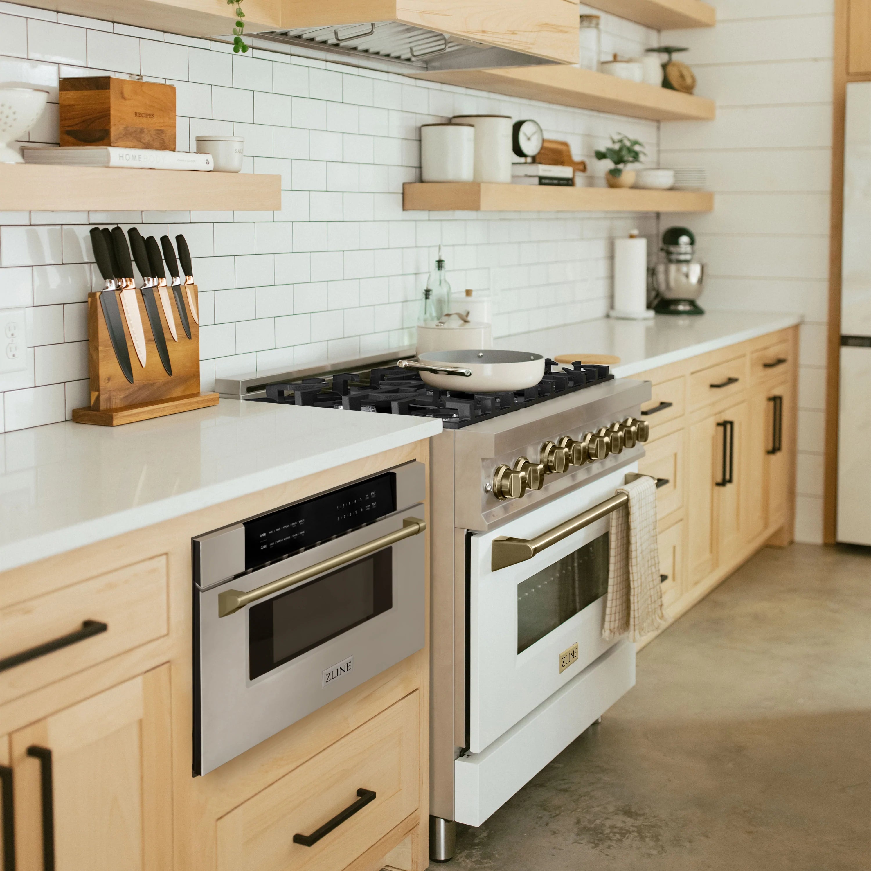 Built-in microwave drawer installed in cabinetry, stainless steel with champagne bronze handle trim