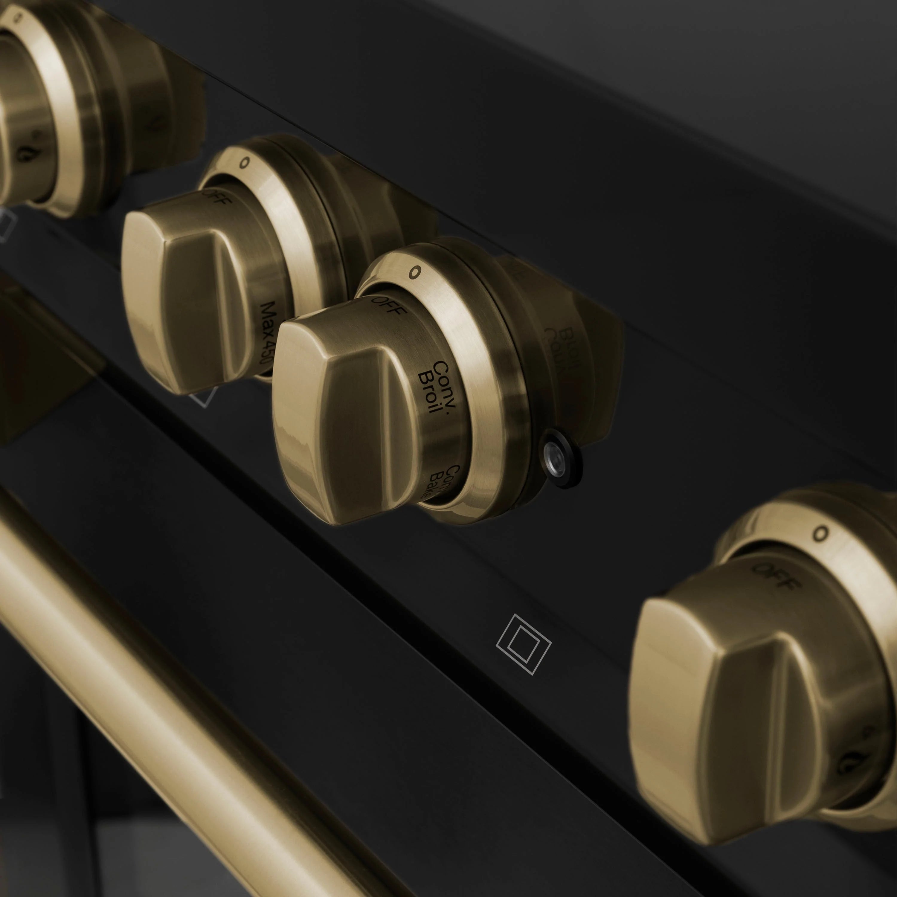 Champagne bronze range control knobs on a black panel with indicator icons.