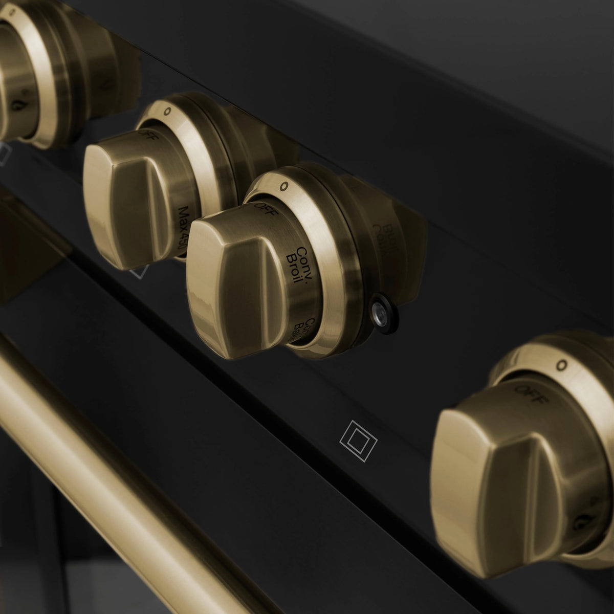 Close-up of black range control panel with champagne bronze rotary knobs