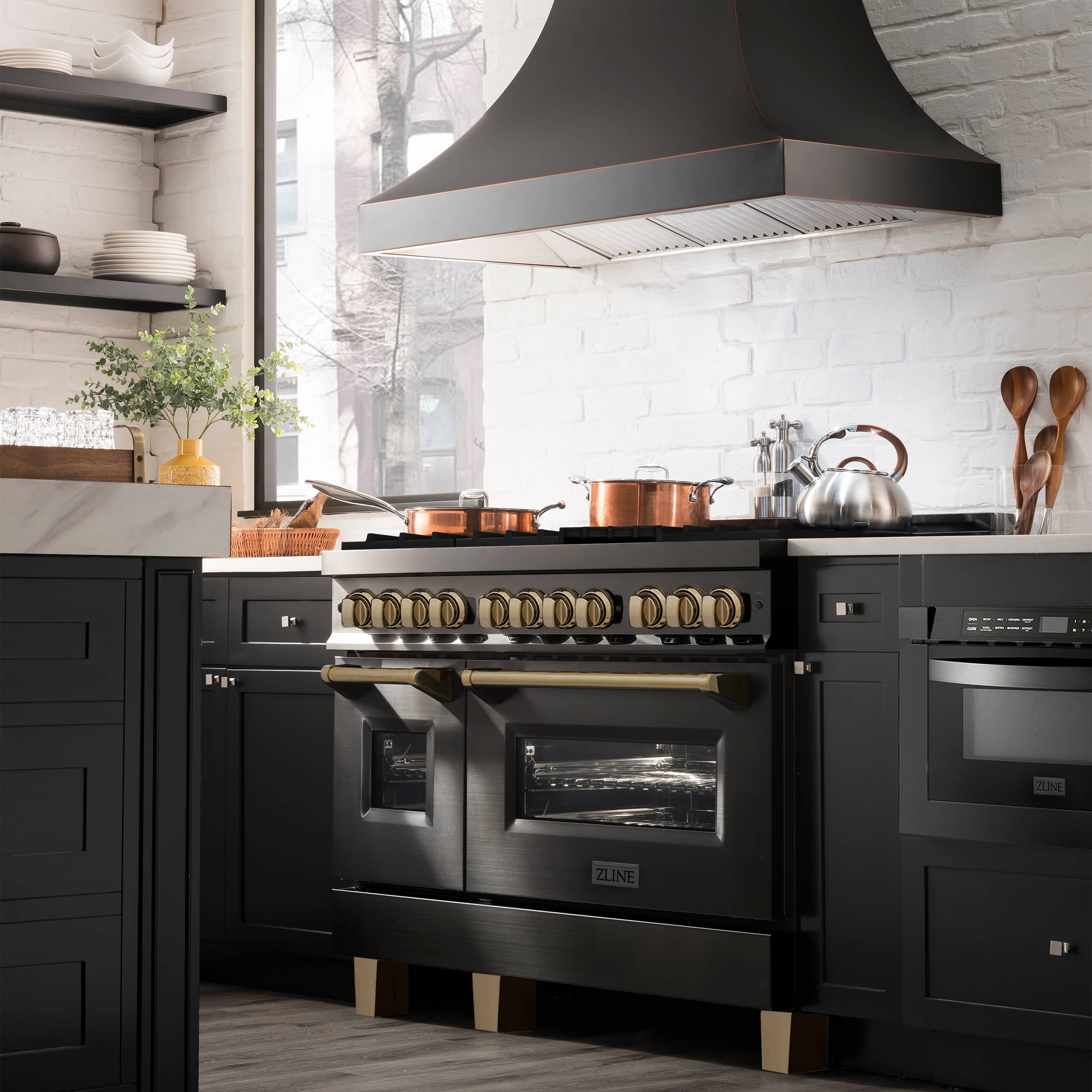 Black stainless dual fuel range with lit burner grates and champagne-bronze control knobs