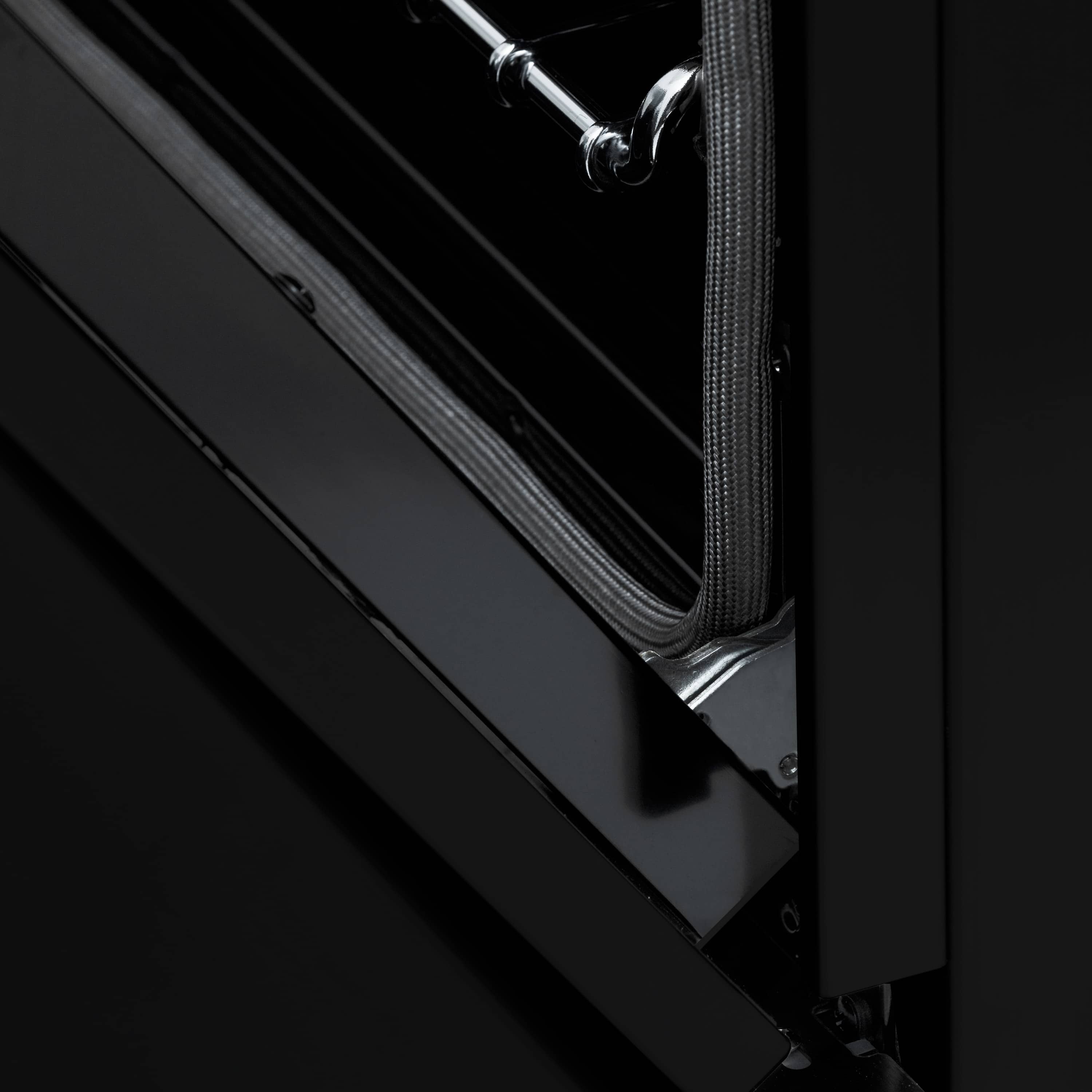 Black oven door edge with gold-trimmed handle and metal hinge hardware